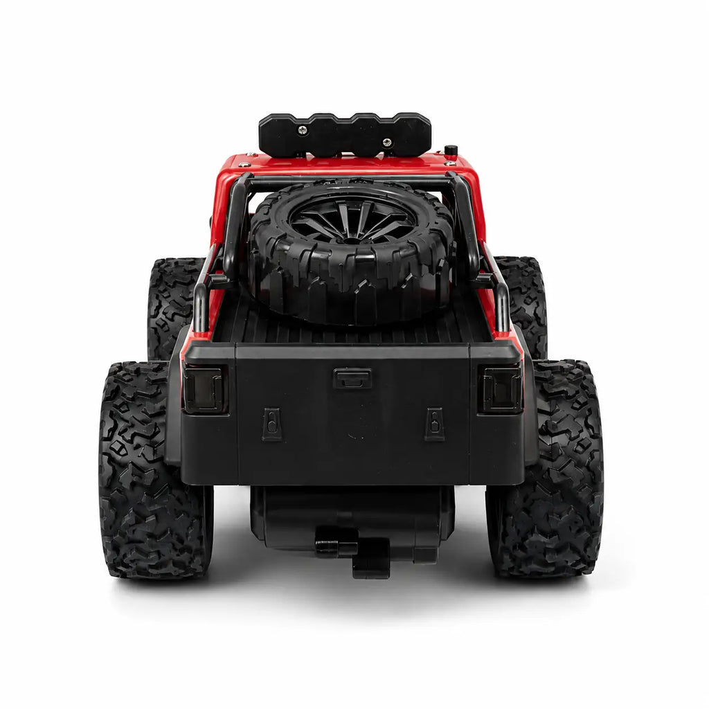 Rear view of a red and black toy off-road truck with large black tires and a spare tire mounted in the bed, shown on a white background.